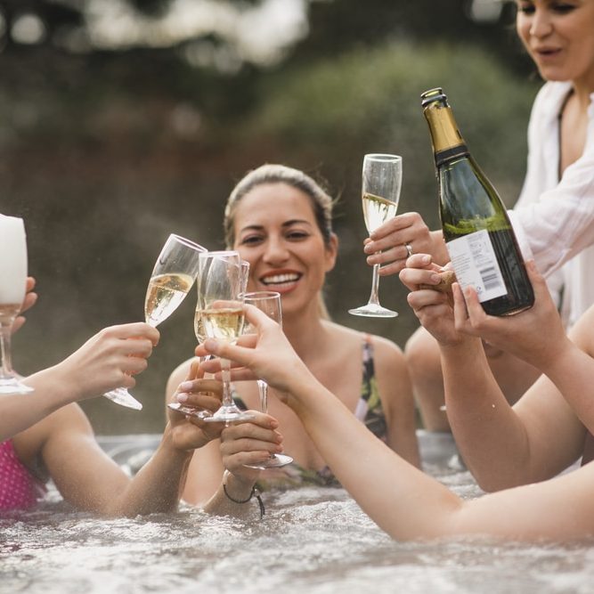 A group of friends clinking glasses while enjoying a celebration in a hot tub.