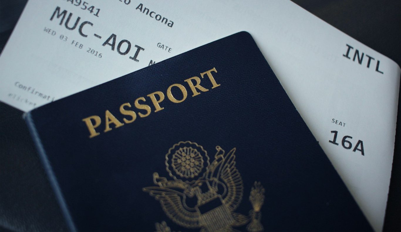 A dark blue passport and flight boarding pass on a surface.