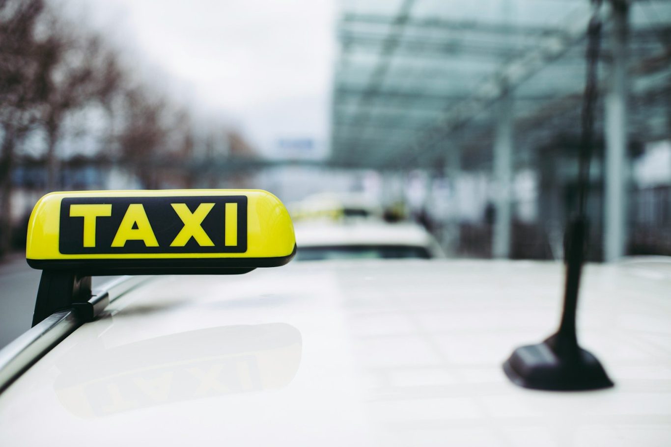 Taxi sign displayed prominently on a car roof in an urban setting.
